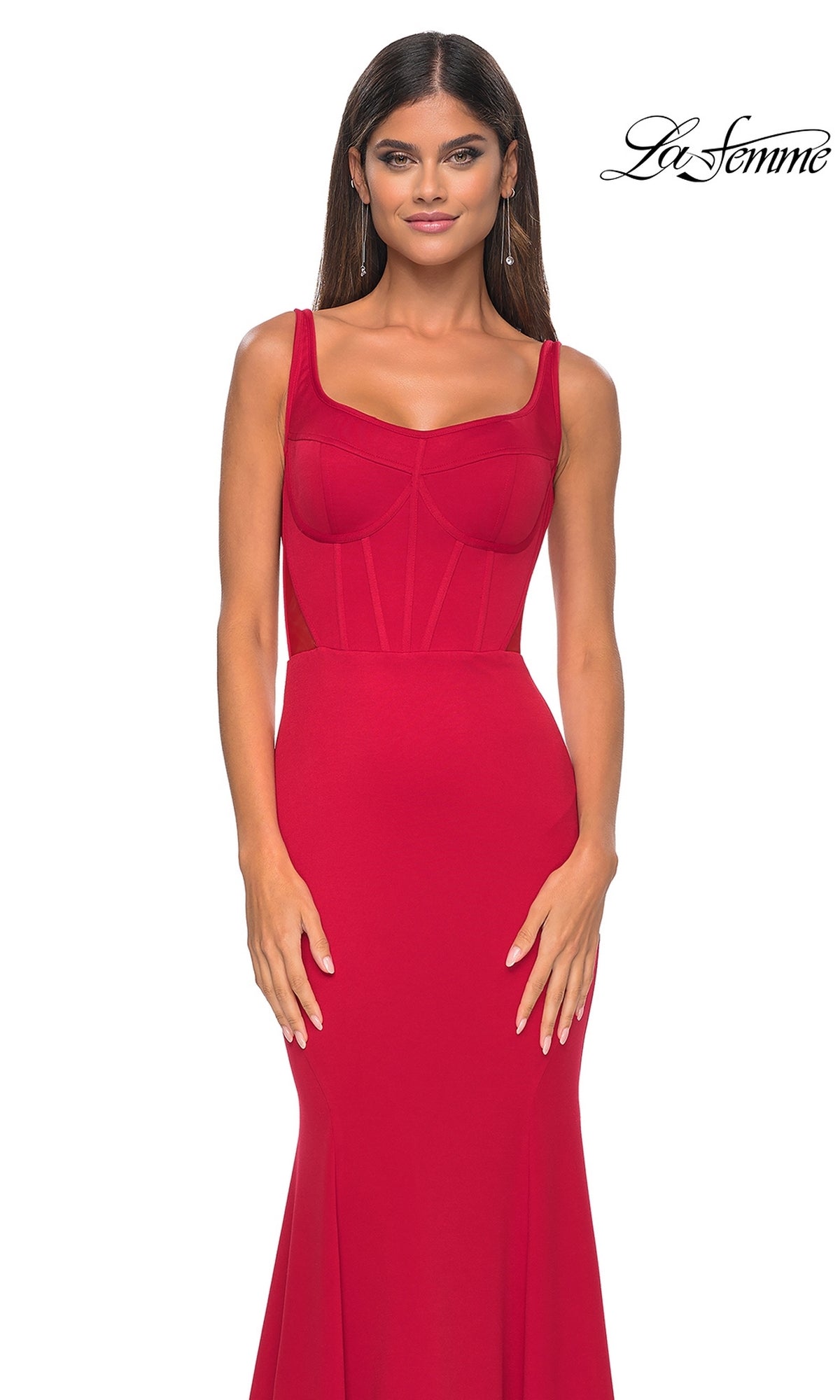 A woman models the La Femme Lace-Up Sheer Back Long Prom Dress 32268, a fitted red sleeveless gown with a corset-style bodice, standing against a white background featuring the